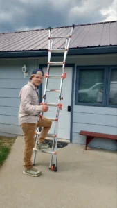 roofing professional standing beside an extension ladder at a home
